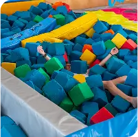 Child buried in colorful foam pit at indoor trampoline park