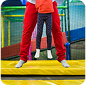 Adult helping a child jump on a trampoline in an indoor play area