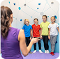 Instructor guiding children in front of a climbing wall at an indoor activity center