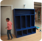 Child near a blue cubby shelf in an indoor play facility