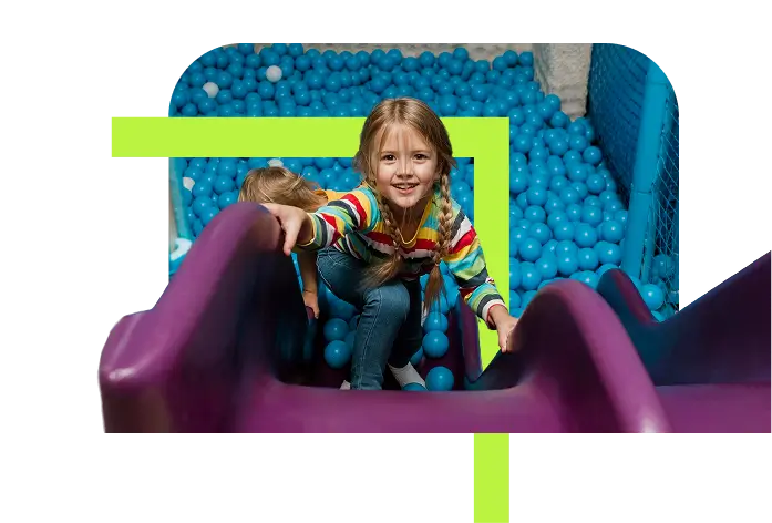 Smiling girl playing in ball pit and slide at Flyout Trampoline Park